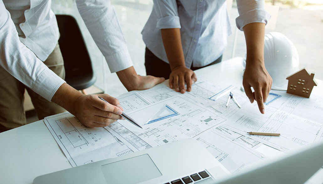 Structural engineering designers are working on the blueprints and analyzing them together.