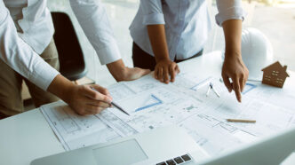 Structural engineering designers are working on the blueprints and analyzing them together.