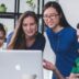 four people watching on white MacBook on top of glass-top table