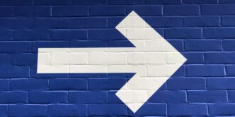white arrow painted on brick wall