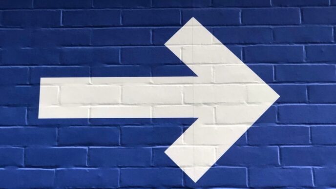 white arrow painted on brick wall