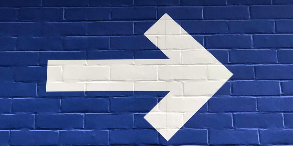 white arrow painted on brick wall