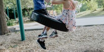 girl in pink and white floral dress riding on swing during daytime