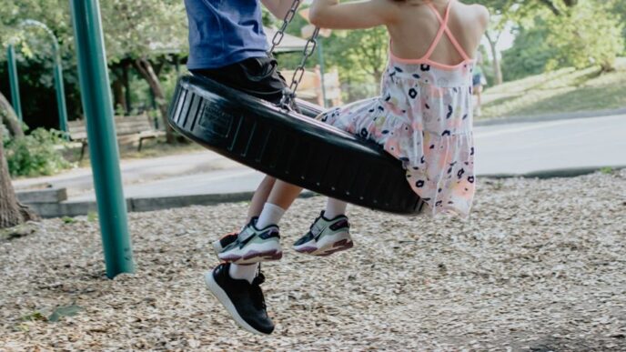 girl in pink and white floral dress riding on swing during daytime