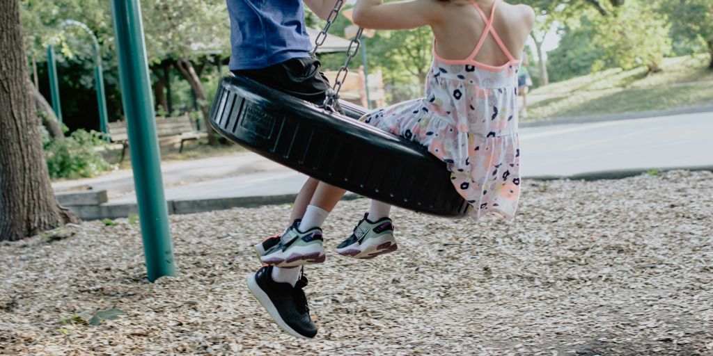 girl in pink and white floral dress riding on swing during daytime