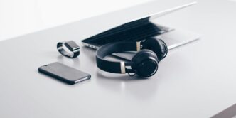 black cordless headphones beside closed black laptop computer and smartphone