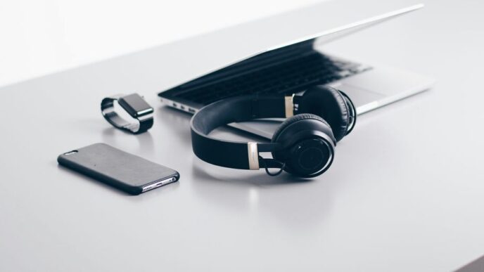 black cordless headphones beside closed black laptop computer and smartphone