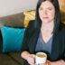 woman holding cup of coffee sitting on sofa