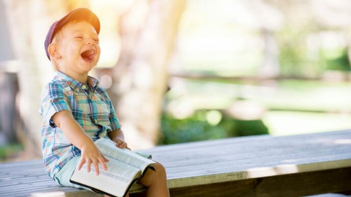 boy sitting on bench while holding a book