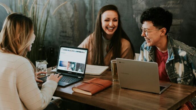 three people sitting in front of table laughing together