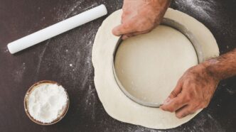 person cutting dough with round cutter