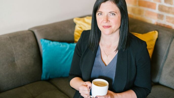 woman holding cup of coffee sitting on sofa