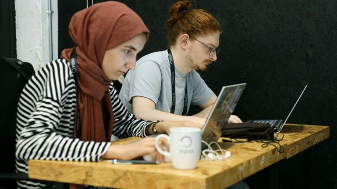 two women sitting at a table with laptops