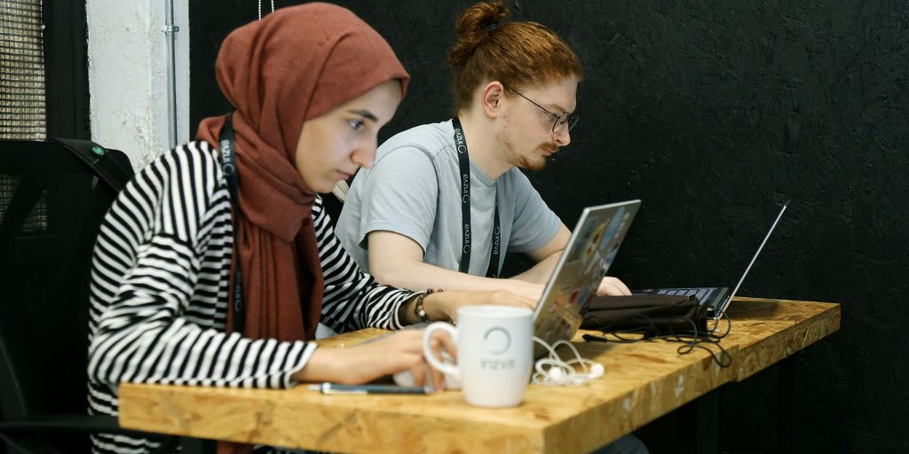 two women sitting at a table with laptops