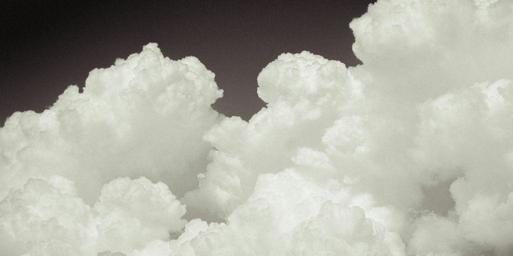 a plane flying through a cloud filled sky