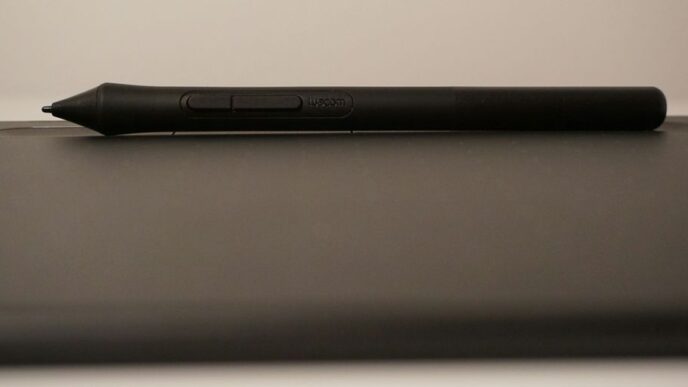 a black pen sitting on top of a laptop computer