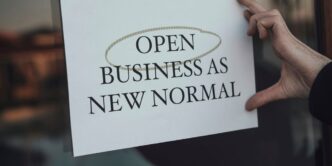 a person holding a sign that says open business as new normal