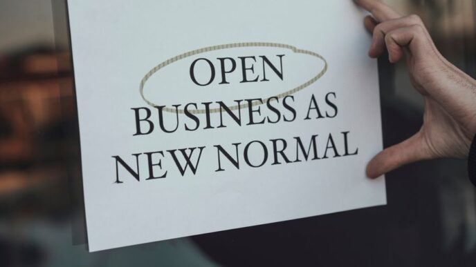 a person holding a sign that says open business as new normal