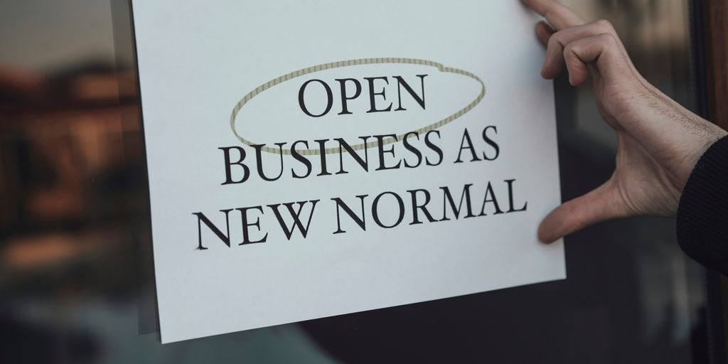 a person holding a sign that says open business as new normal