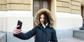 a woman in a parka holding a cell phone