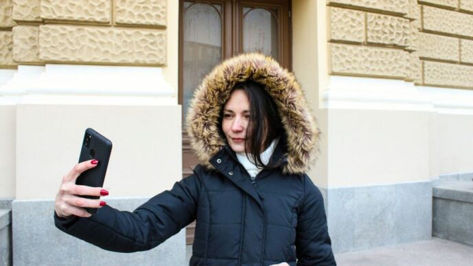 a woman in a parka holding a cell phone