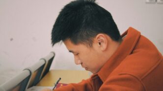 man in orange hoodie using smartphone