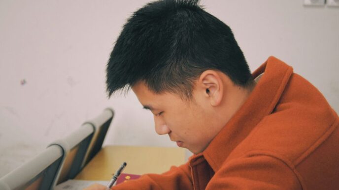 man in orange hoodie using smartphone