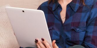 woman in blue denim button up jacket holding white laptop computer