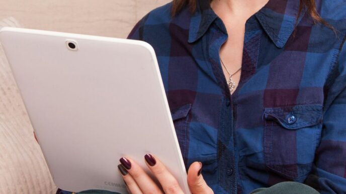 woman in blue denim button up jacket holding white laptop computer