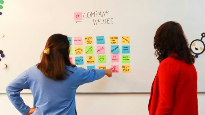 a couple of women standing in front of a white board