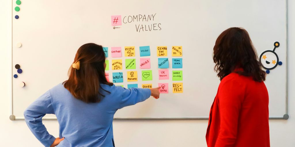 a couple of women standing in front of a white board