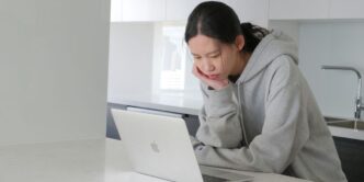 man in gray hoodie sitting beside white table