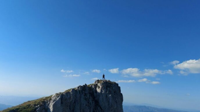 person standing on rock formation under blue sky during daytime