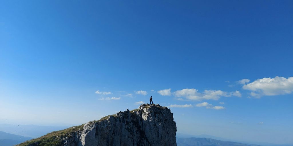 person standing on rock formation under blue sky during daytime