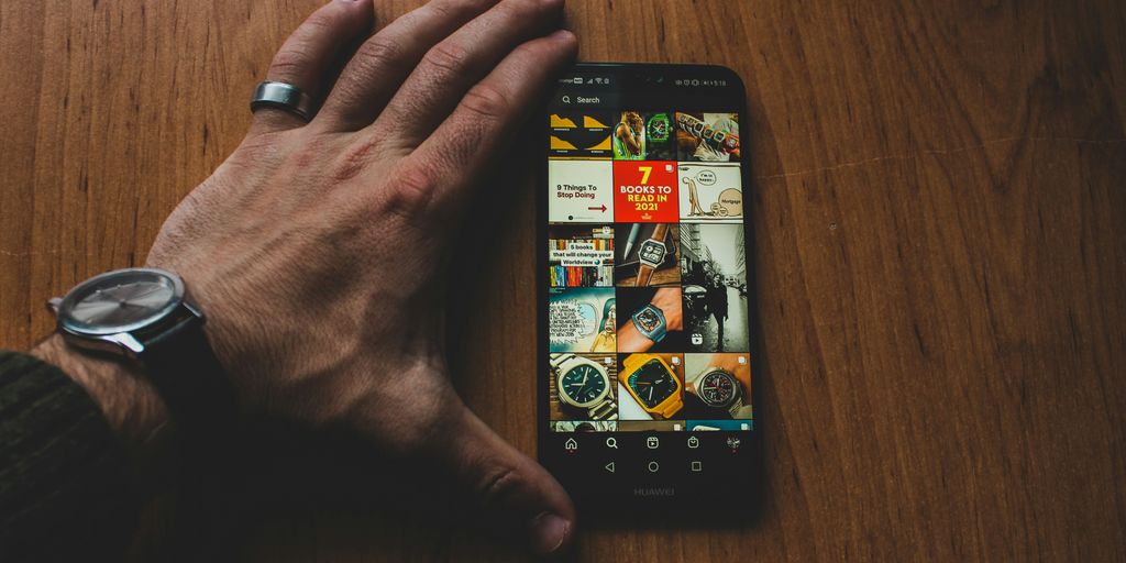 a person holding a smart phone on top of a wooden table