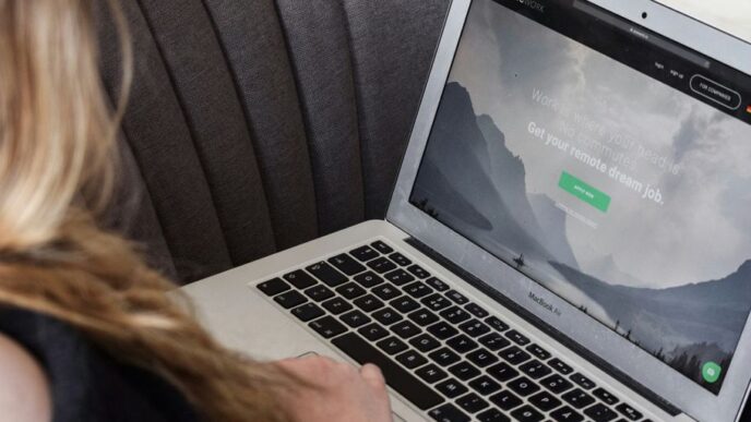person using macbook air on gray couch