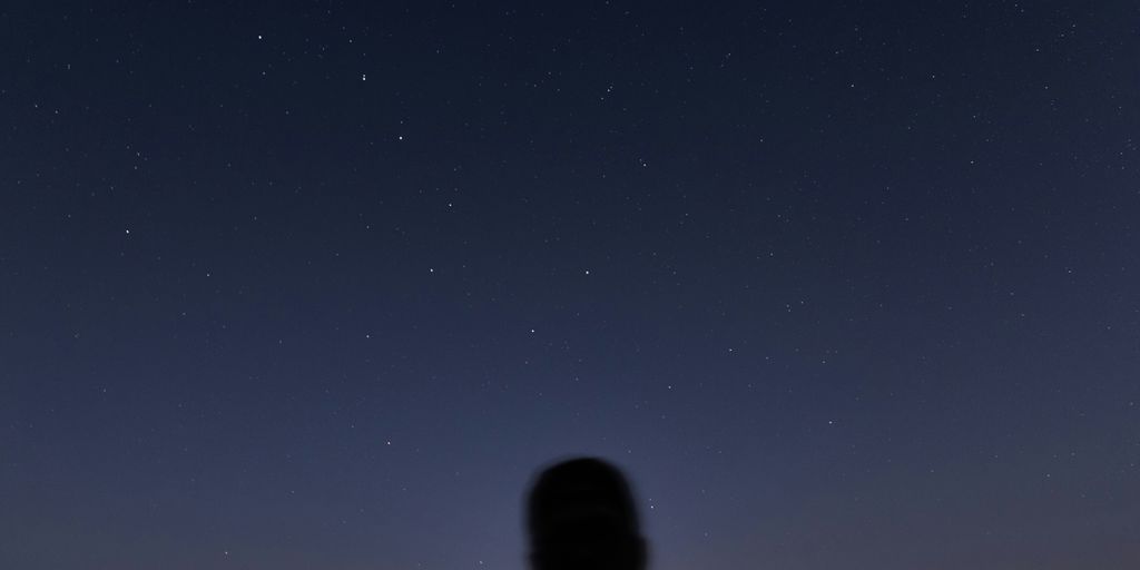 man in black jacket standing under blue sky during night time
