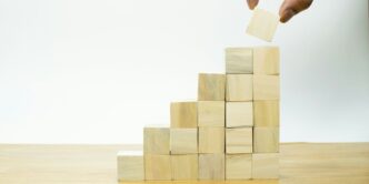 A person placing a piece of wood into a pyramid