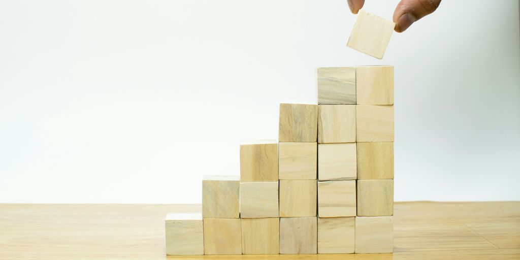 A person placing a piece of wood into a pyramid