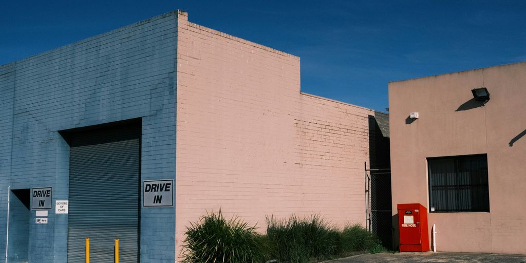 a pink building with a blue door and a red door