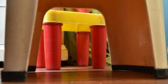 a child's chair with a yellow seat and red legs
