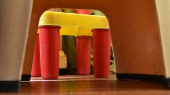 a child's chair with a yellow seat and red legs
