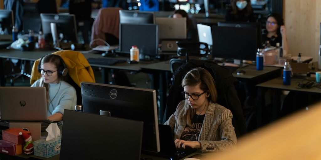 a group of people working on laptops in an office