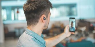 shallow focus photo of man in gray collared top taking selfie
