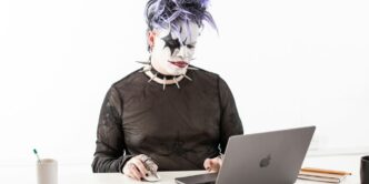 a person in a cat mask sitting in front of a laptop