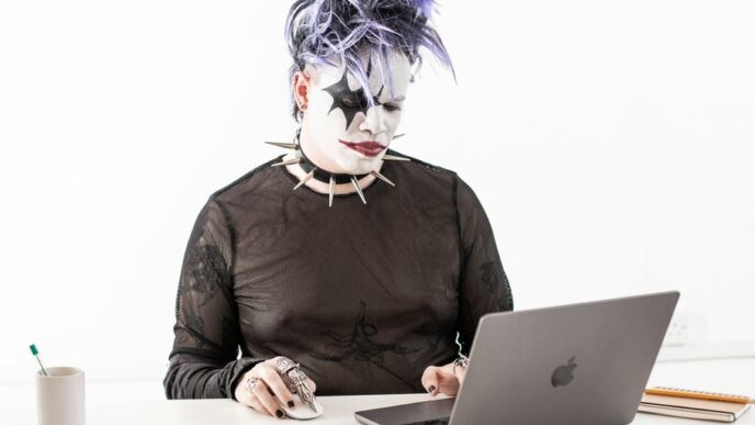 a person in a cat mask sitting in front of a laptop