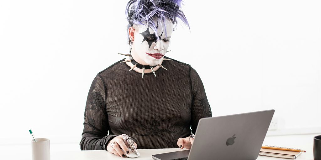 a person in a cat mask sitting in front of a laptop