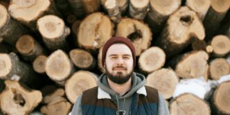 man standing behind firewoods