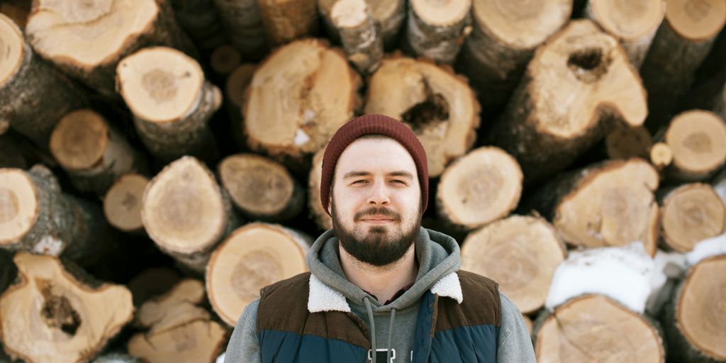 man standing behind firewoods
