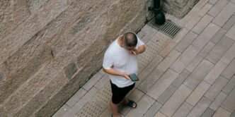 a man standing next to a wall talking on a cell phone